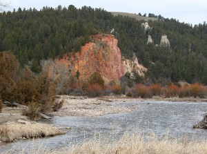 An outcropping of red stone forms a cliff along a river in Southwest Montana.